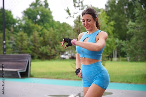 Fototapeta Naklejka Na Ścianę i Meble -  happy active girl runner, young fit woman is jogging, running outdoors, checking her smart watches at wrist, looking at smartwatches, tracking pulse, measuring heartbeat, heart rate after workout