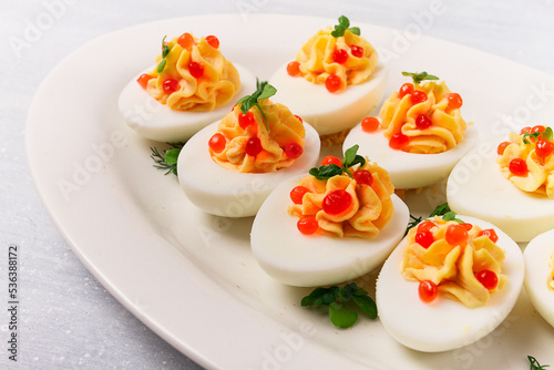 Stuffed eggs, with red caviar, micro greenery, Snack, on a white plate, top view, close-up, no people,