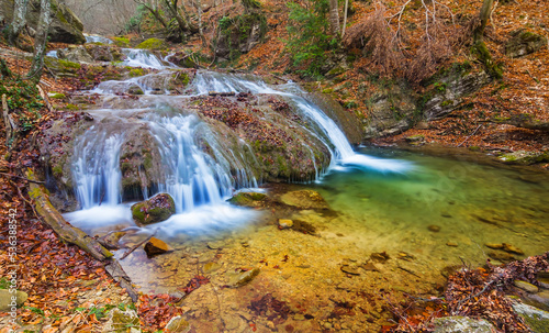 small waterfall on mountain river flow through autumn mountain canyon © Yuriy Kulik