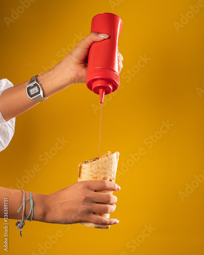 hand holds shawarma. girl adds ketchup