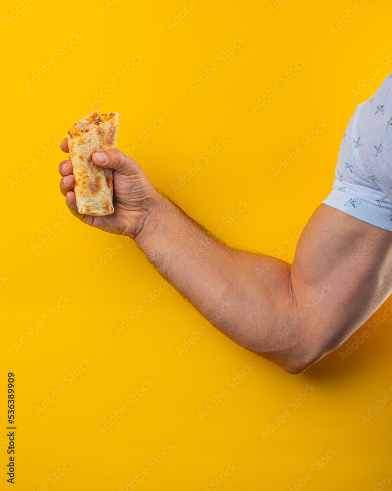 muscular hand holds shawarma.