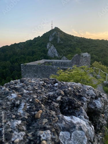 Vertical shot of Vrsatec castle ruins in green mountains of Slovakia at sunset photo