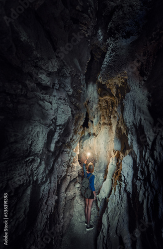 Canvas Print Young woman exploring a cave digged in the mountain.