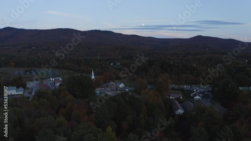 An aerial drone shot of Waterbury, Vermont at dusk.  The moon hangs over the mountains on this autumn night. photo