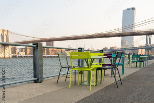Table and chairs on the East River boardwalk overlooking the Brooklyn Bridge