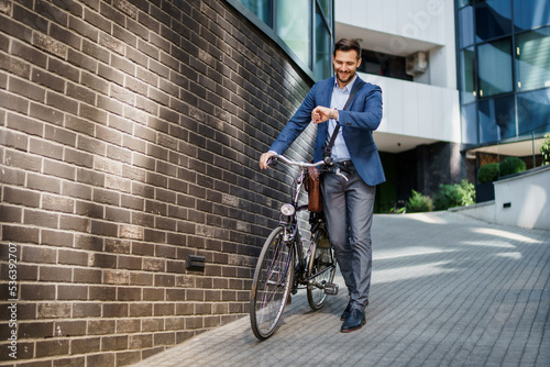 Happy middle age caucasian stylish businessman going to work by bike.