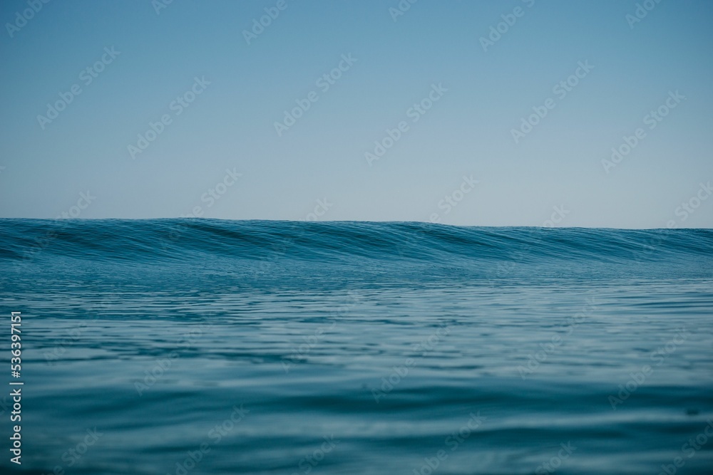 Obraz premium Gorgeous view of a bright blue sea with calm tides rising slowly rising under a clear sky
