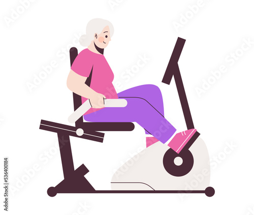 Elderly lady rides stationary bicycle. Senior active lifestyle concept.