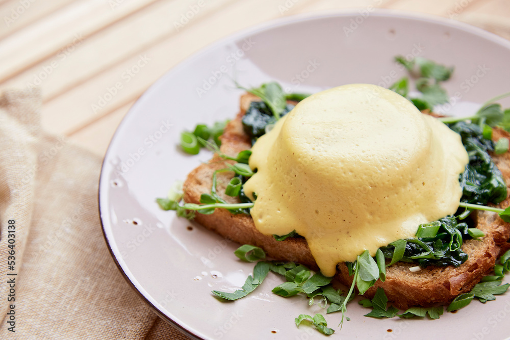 Vegan eggs benedict dish with wholegrain bread, smoked tofu, young onion, parsley, greens, pea sprouts outside. Vegan eggs benedict dish with wholegrain bread, smoked tofu, young onion, parsley, greens, pea sprouts outside.