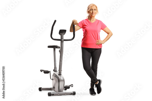 Mature woman in sportswear leaning on a stationary bike