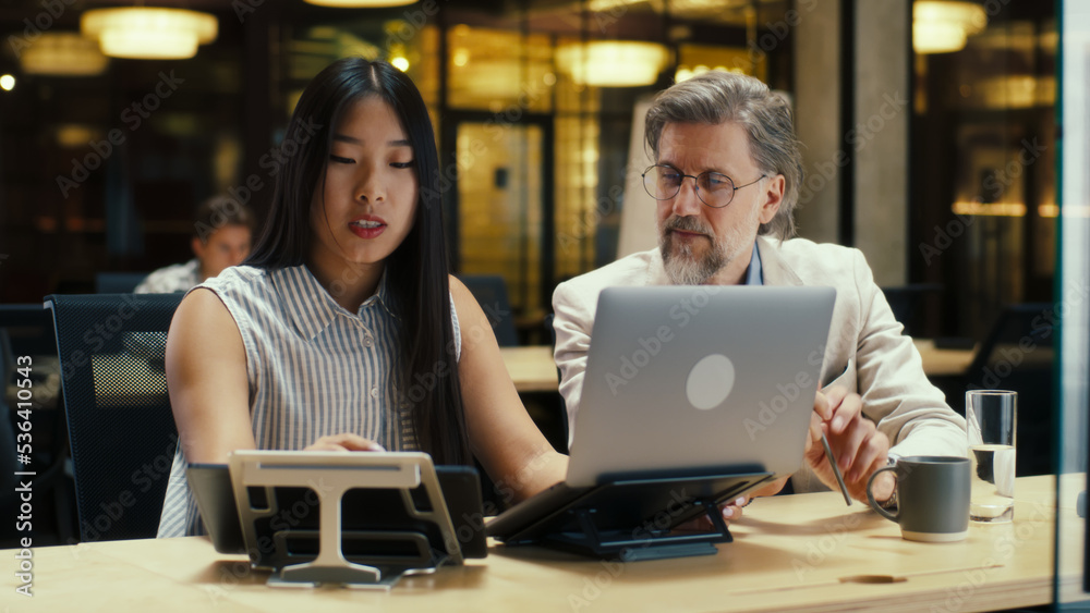 Multi-ethnic entrepreneurs discussing business startup project in modern office using laptop and digital tablet computer. E-commerce company. Teamwork on business strategy