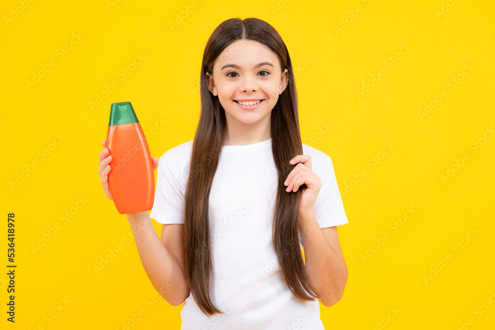 Teenager child girl showing bottle shampoo conditioners or shower gel. Hair cosmetic product. Bottle for advertising mock up copy space. Happy teenager portrait. Smiling girl. Teenager child girl showing bottle shampoo conditioners or shower gel. Hair cosmetic product. Bottle for advertising mock up copy space. Happy teenager portrait. Smiling girl.