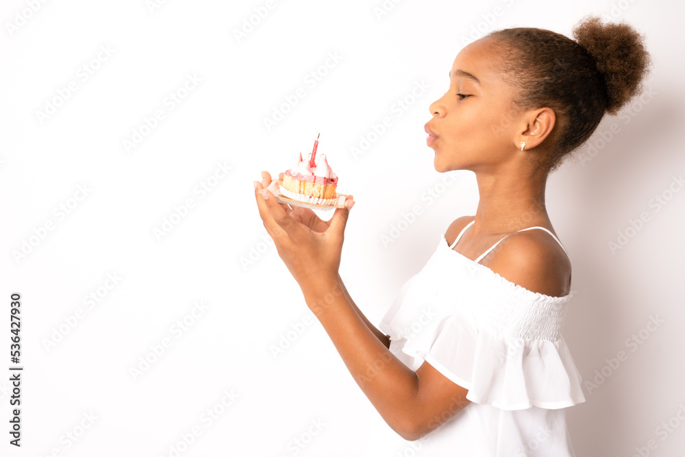 Cute adorable child african american girl celebrating birthday while holding strawberry cake and blowing standing isolated over white background Cute adorable child african american girl celebrating birthday while holding strawberry cake and blowing standing isolated over white background
