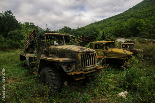 Old abandoned rusty military trucks overgrown by plants