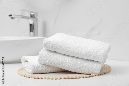 Folded bath towels on white table in bathroom