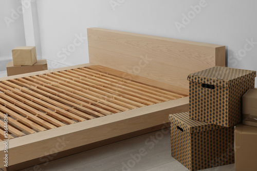 New wooden bed frame and moving boxes indoors