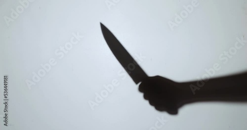 The shadow of a murderer kills his victim with a knife at night.
