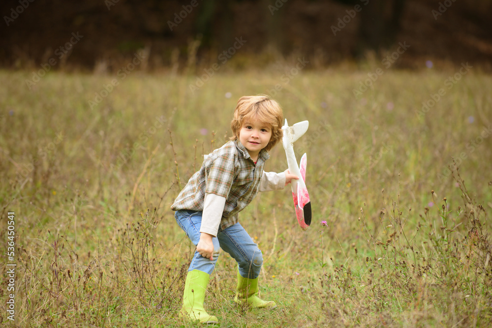 Child pilot with toy airplane dreams of traveling in summer in nature. Kids dreams. Kid having fun with toy airplane in field. Childhood dream imagination concept. Child pilot with toy airplane dreams of traveling in summer in nature. Kids dreams. Kid having fun with toy airplane in field. Childhood dream imagination concept.