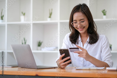 Young Asian businesswoman enjoy shopping online using credit card at a coffee shop.