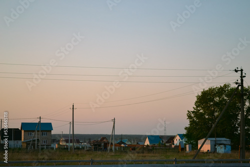A beautiful rural landscape with houses and power lines against the background of an evening clear sky