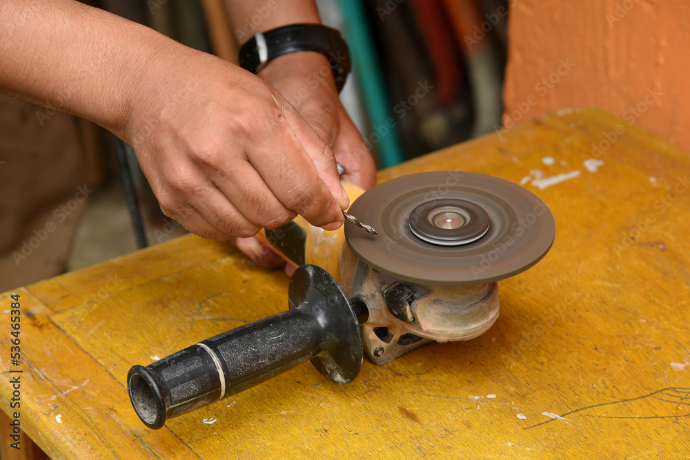 sharpening drill bit on an electric grinder on a wooden bench.Close-up sharpening drill bit on an electric grinder on a wooden bench.Close-up