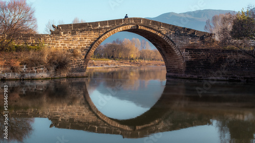 Photography An old bridge over the reflecting water, at dawn in the fall of Yunan Province, China