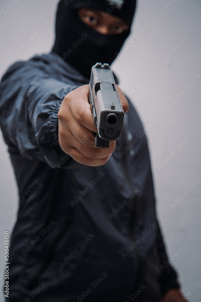 Burglar or terrorist. Holding pistol in various poses on background isolated with clipping path. Burglar or terrorist. Holding pistol in various poses on background isolated with clipping path.