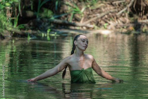 Fototapeta Naklejka Na Ścianę i Meble -  Portrait of a young beautiful dark-haired girl posing in the river.