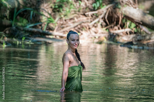 Fototapeta Naklejka Na Ścianę i Meble -  Portrait of a young beautiful dark-haired girl posing in the river.