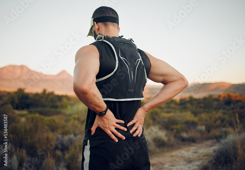 Muscle, injury and back pain after a workout or running outdoor. Man holding lower back muscles in pain after exercise, hike and run. Accident, hurt and physical strain for backache during exercise photo