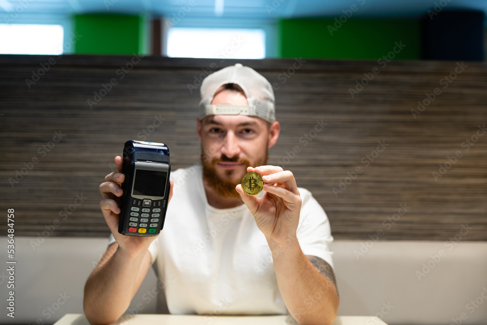 A young man is debating whether to use a credit card or cryptocurrency for payment. Card payment versus bitcoin.