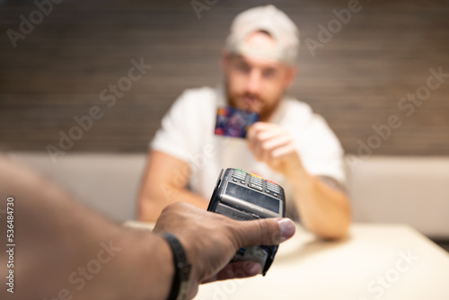 Obraz na płótnie A young man is debating whether to use a credit card or cryptocurrency for payment. Card payment versus bitcoin. w salonie