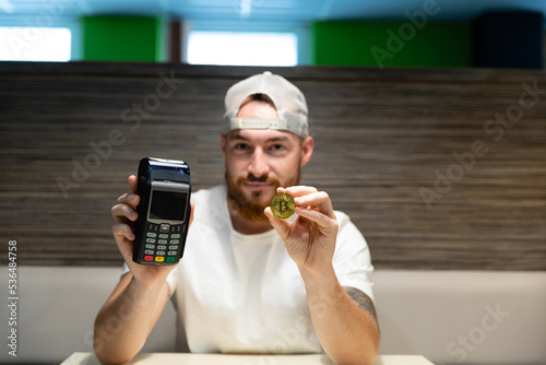Obraz na płótnie A young man is debating whether to use a credit card or cryptocurrency for payment. Card payment versus bitcoin. w salonie