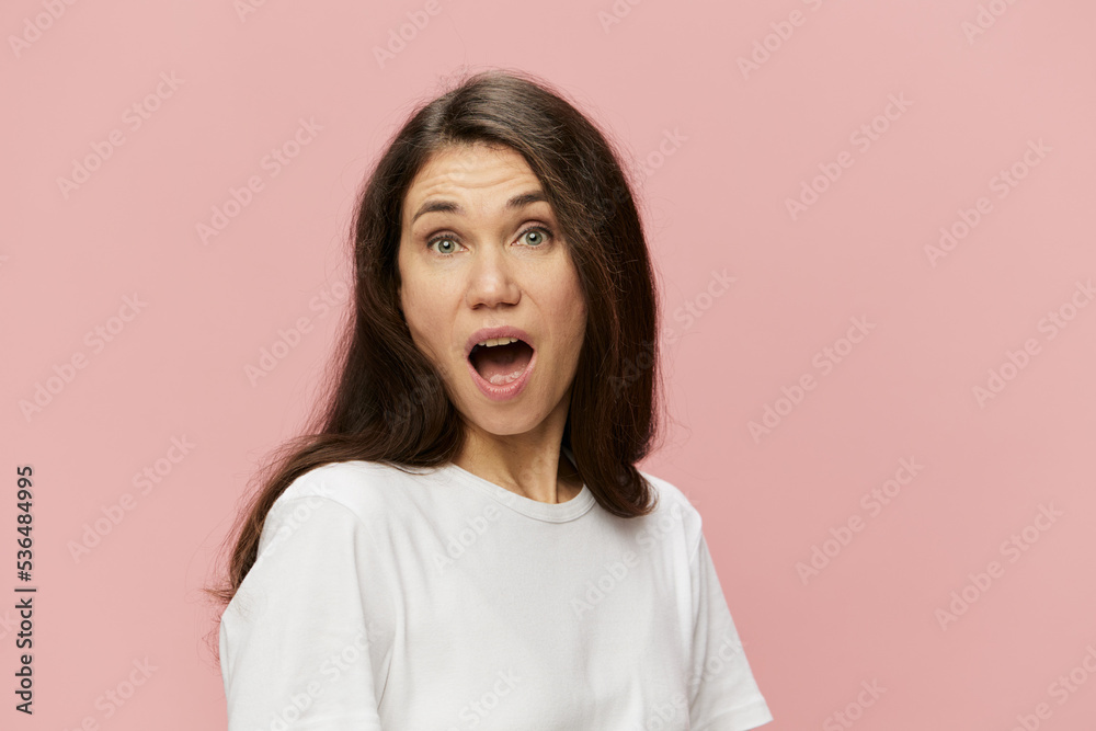 horizontal portrait of a cute, attractive, emotional woman on a pink background in a clean white t-shirt, with her mouth wide open