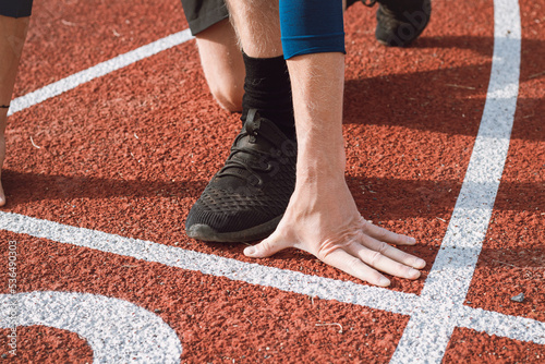 Detail of a professional athlete's hand position at the start of a 100m sprint. Outdoor athletics oval