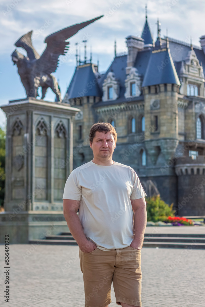 Fototapeta premium A man on the background of a Gothic-style castle. The territory of the tourist complex