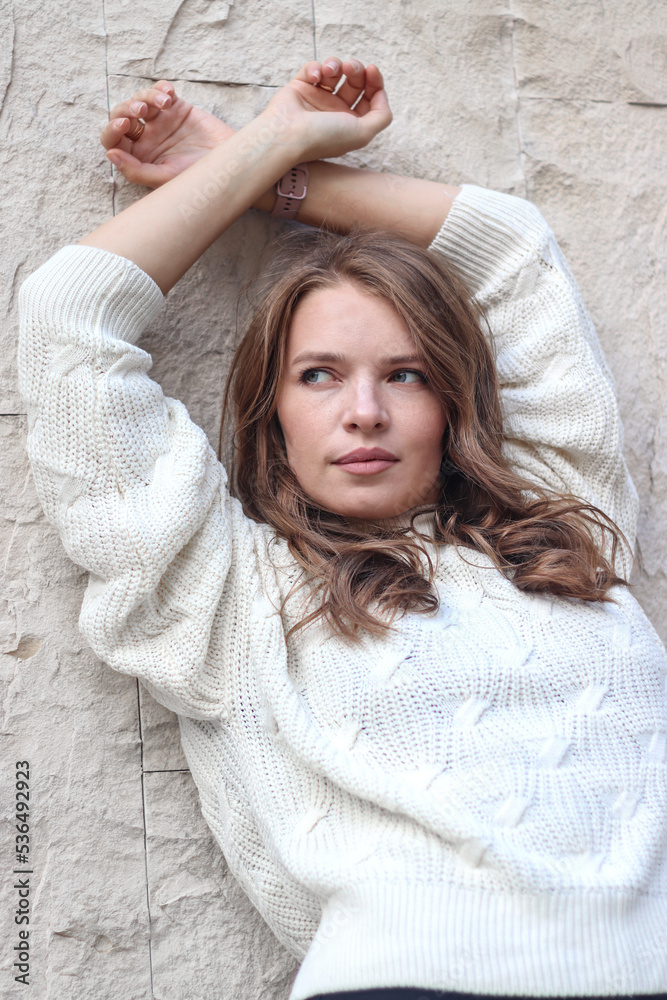 Street photo session of a girl with blond long hair in a beige coat. Photo shoot in the big city.