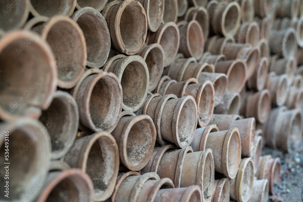 Closeup of stacks of old used weathered terra cotta flower pots in gardening shed. Empty vintage flowerpots. Closeup of stacks of old used weathered terra cotta flower pots in gardening shed. Empty vintage flowerpots.