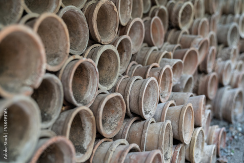 Closeup of stacks of old used weathered terra cotta flower pots in gardening shed. Empty vintage flowerpots.