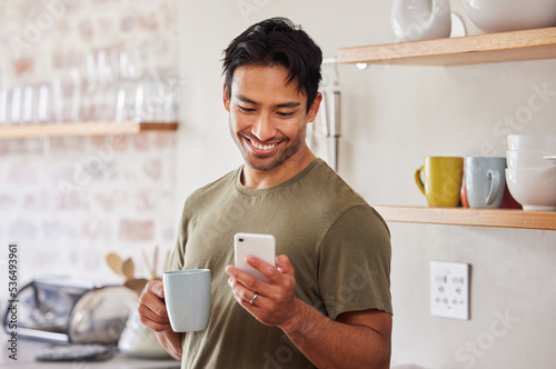 Vászonkép Phone, coffee and social media with a man in his kitchen in the morning while reading a message in his home