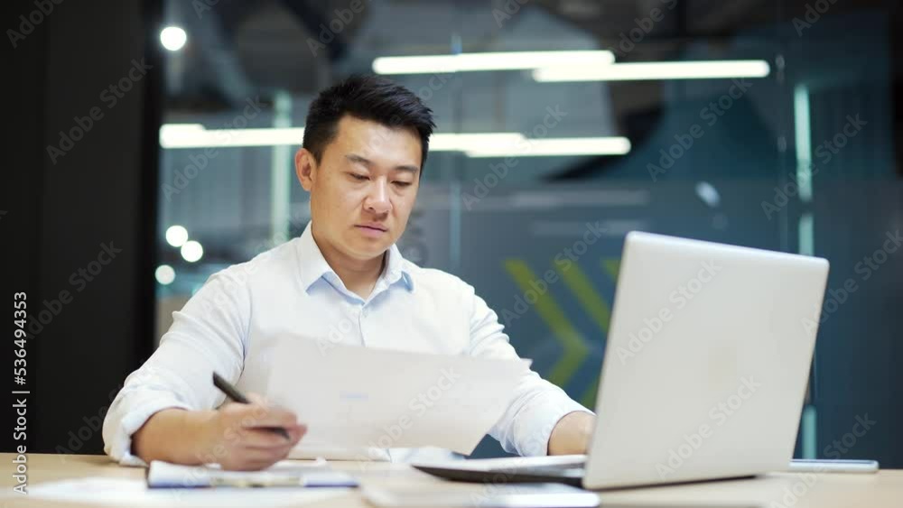 Busy employee, accountant booker working in office workplace counting profit taxes paperwork routine Concentrated asian male entrepreneur manager analyzing statistics in paper report, doing financial Busy employee, accountant booker working in office workplace counting profit taxes paperwork routine Concentrated asian male entrepreneur manager analyzing statistics in paper report, doing financial
