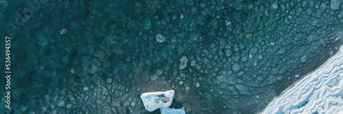 Top view of the freezing sea. Aerial view of ice floes in sea water near an icy seashore. Nature of the Extreme North and the Arctic. Cold frosty winter weather. Natural background. Wide panorama.