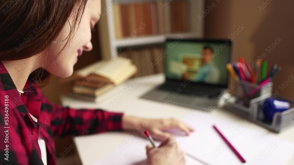 distance learning online education. girl student studying at home on a laptop watching an school online seminar near a bookcase desk online. distance education concept. teen girl on an online exam distance learning online education. girl student studying at home on a laptop watching an school online seminar near a bookcase desk online. distance education concept. teen girl on an online exam