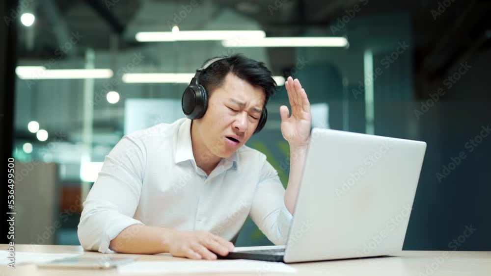 excited asian businessman cheering for game looking at laptop computer screen in office Male employee in headphones fail in sports betting fan watches an online match failure bad result soccer excited asian businessman cheering for game looking at laptop computer screen in office Male employee in headphones fail in sports betting fan watches an online match failure bad result soccer