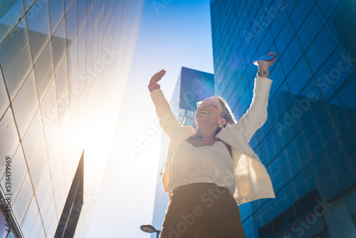 Happy business woman celebrating success with raised arms.