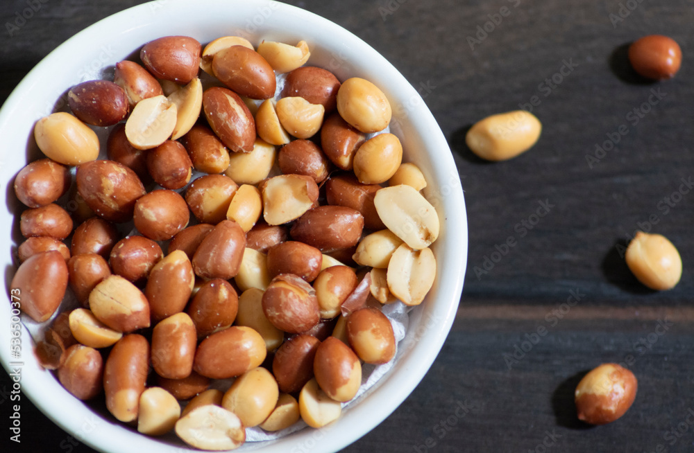 roasted peanuts in white cup on dark wooden floor