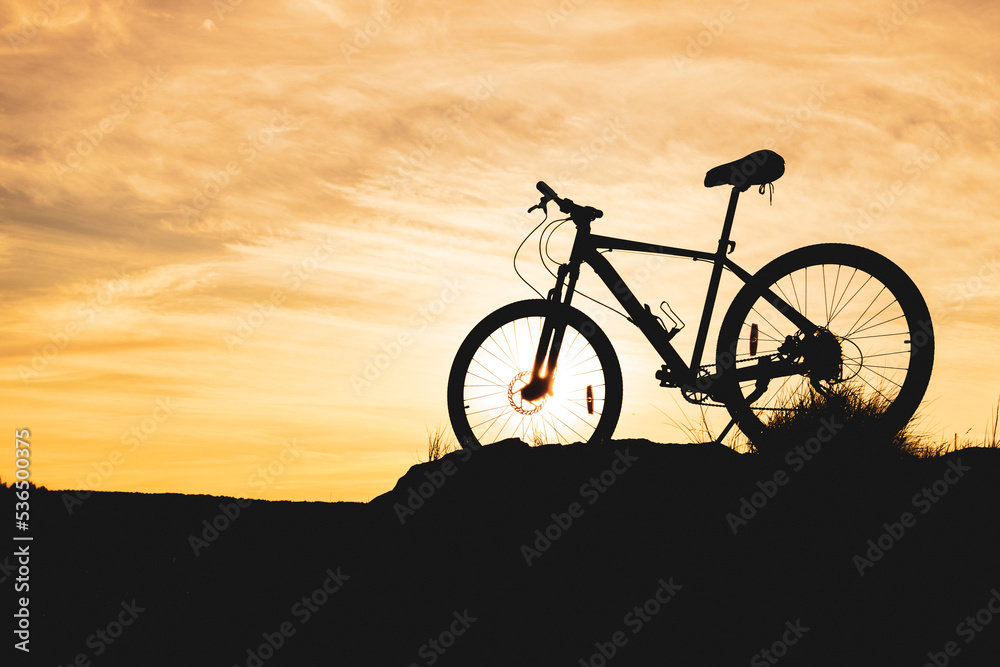 against the background of a blurred sunset sky, the silhouette of a bicycle against the background of a blurred sunset sky, the silhouette of a bicycle