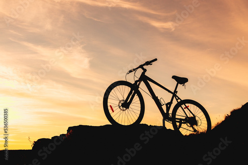 silhouette of a bicycle on a mountain  the background is a blurred sky in the evening