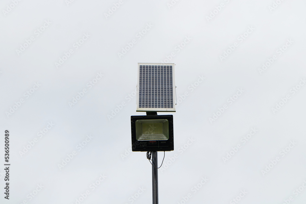 Solar panel powered street light bulbs side walking street in park. Concept of saving electricity by using solar energy as renewable energy. Sky cloud was overcast is background. Solar panel powered street light bulbs side walking street in park. Concept of saving electricity by using solar energy as renewable energy. Sky cloud was overcast is background.
