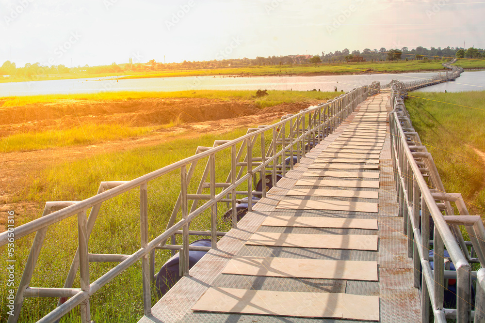 Fototapeta premium Bridge over the river with bright sky and bright sunset